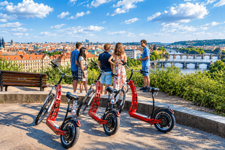 Group with scooters enjoys city and river view from hill.