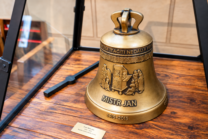 Decorative bronze bell with engravings on a wooden display.
