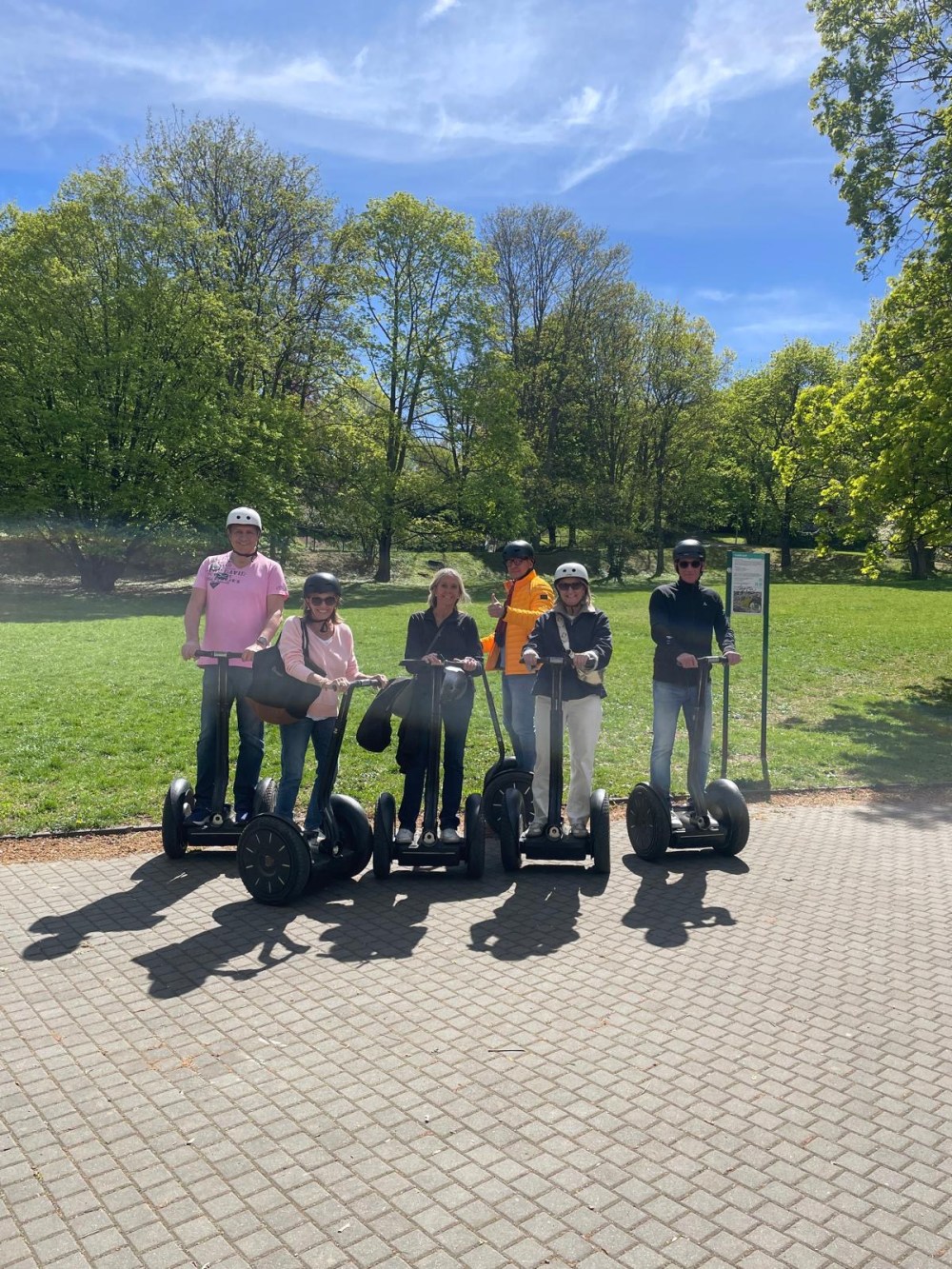 Group on Segways in a sunny park with trees and grass.