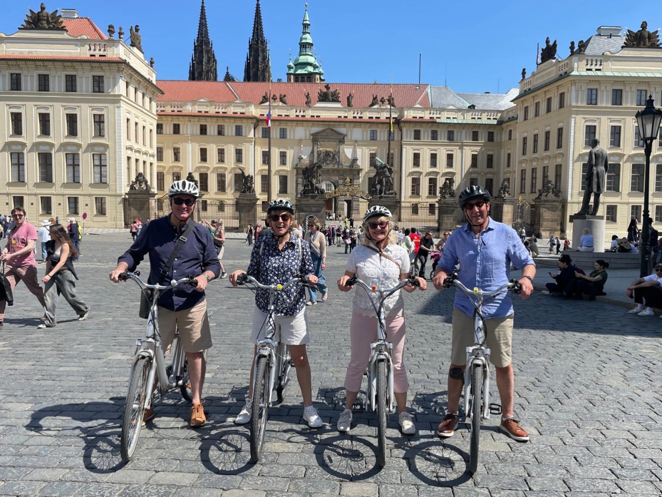 Four people with bikes pose in front of a historic building.