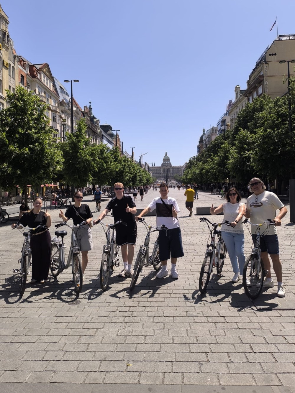 Group of people with bikes on a city street, sunny day.