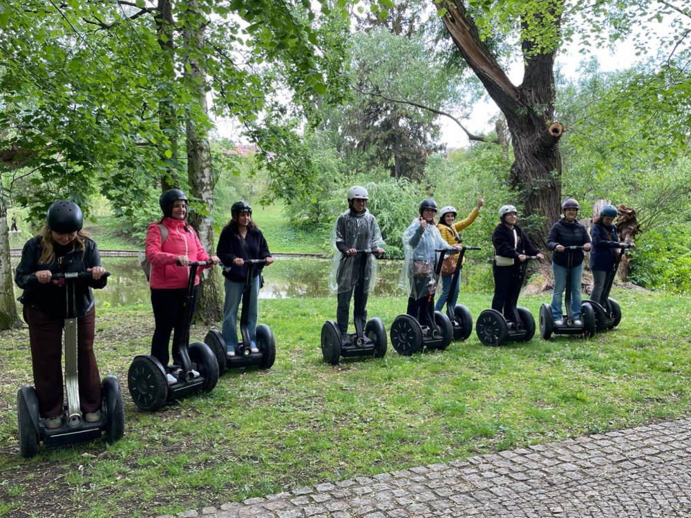Group of people on Segways in a park with trees.