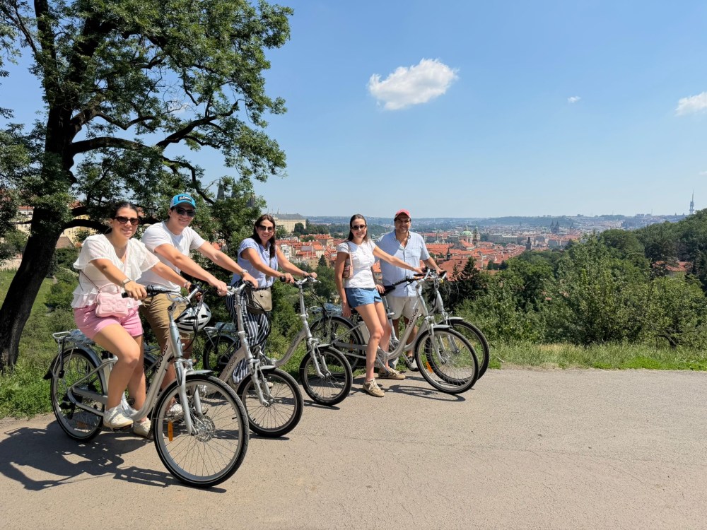 Group of five people on bikes with a cityscape in the background.