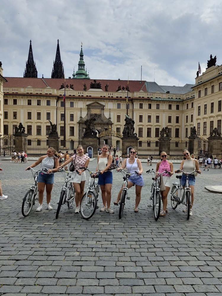 Group of six people on bicycles in front of a historic building.