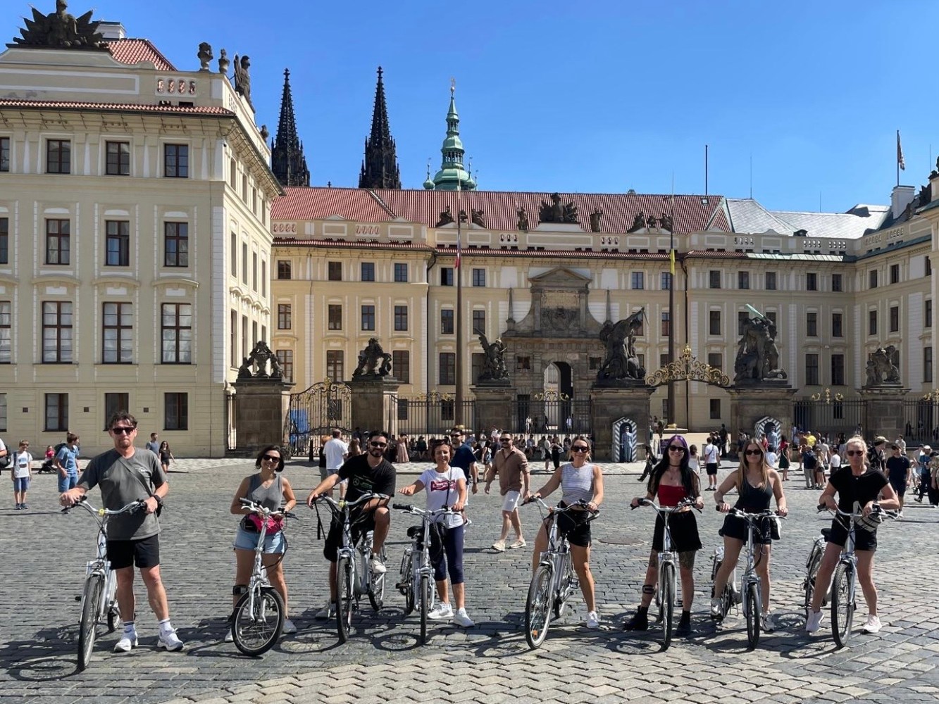 Group of cyclists pose in front of a historic building.