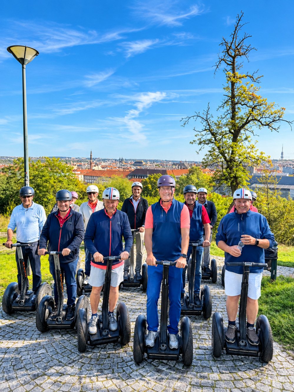 Group of nine people on Segways in a park under a blue sky.