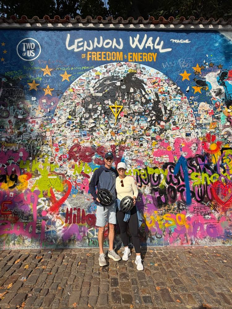 Two people with bikes in front of a colorful graffiti wall.